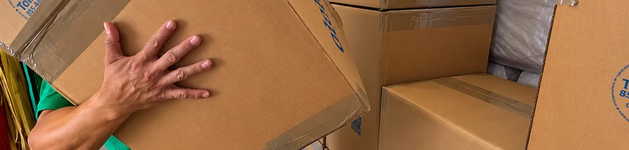 Packed Moving Boxes Loaded in the Van | Oler Relo Moving A mover's hand steadying stacked cardboard moving boxes packed inside an Oler Relo moving van