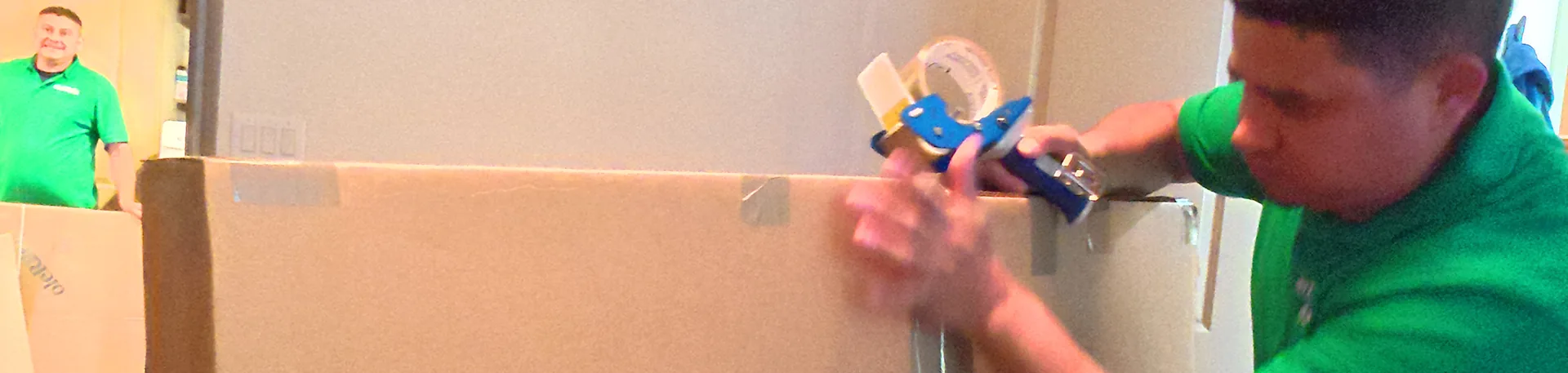 Getting Started on Your Interstate Move | Oler Relo Moving Oler Relo Moving crew taping a large moving box shut before an interstate move
